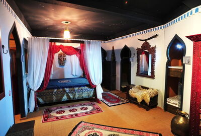 Blick zum Herzstück des historischen Schlaflager. Ein Himmelbett im historisch/orientalischen Stil mit Tüchern und Stoff im gleichen Stil. Dunker Sternenhimmel an der Decke. Vom Hauptraum Zugang zu den vers. Schlafkojen, den Alkoven, mit dunklen Orientali