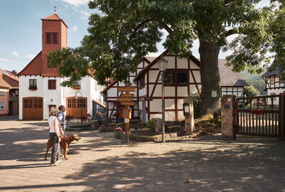 Wanderer mit Hund im Ortskern von Heldra