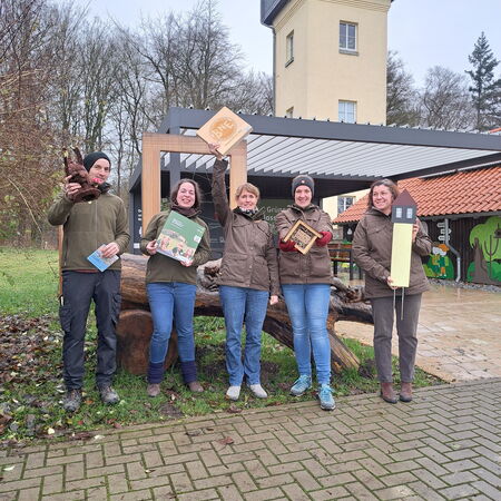 Eine Gruppe von fünf Mitarbeiter des Naturparks Eichsfeld-Hainich-Werratal posiert stolz mit dem Qualitätssiegel 'Bildung für nachhaltige Entwicklung' (BNE) vor dem Naturparkzentrum Fürstenhagen.