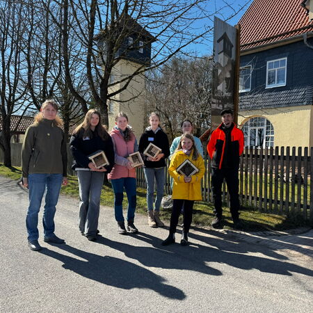 Sieben Personen stehen auf einer Straße vor der gelben Fassade des Naturparkzentrums, einige halten Wildbienen-Nisthilfen in den Händen.