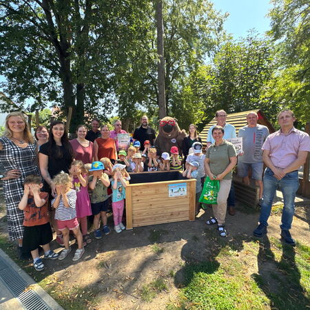 Eine Gruppe Erwachsener und Kinder stehen um ein neues Hochbeet.