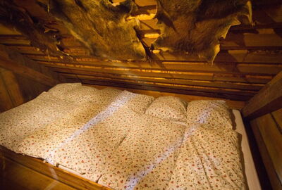 Blick in das historische Schlaflager im Heuboden unter eine Schräge aus Holt. Dekoriert wird die Schräge mit einem Fell. 
Darunter das Schlaflager für 6 Personen inklusive Bettwäsche.