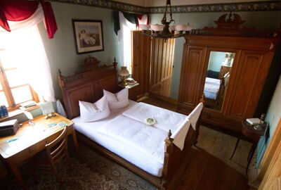 Blick in das Zimmer von oben. 
Historische massive Holzmöbel geben dem Raum das ritterliche Ambiente. 
Historisches Bett, das mit den Schnitzereien an das Mittelalter erinnert. Ein massiver Holzschrank mit Spiegel und ein Schreibtisch aus Holt. Hellgrüne 
